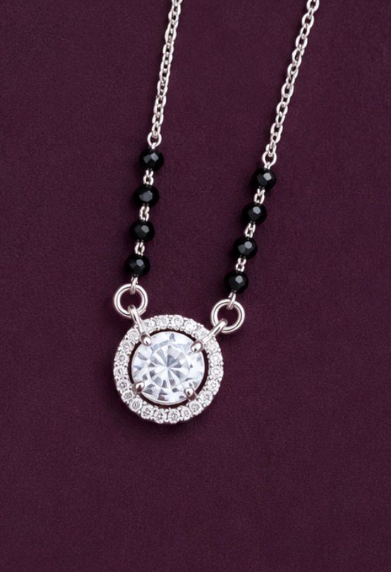 Necklace with a round pendant and black beads on a purple background