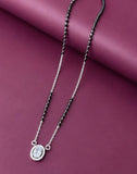 Necklace with black beads and a silver pendant on a purple background