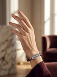 Hand wearing a bracelet with a blurred indoor background