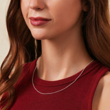 Woman wearing a red top and silver necklace against a neutral background