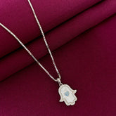 Silver necklace with a hamsa hand pendant on a red fabric background