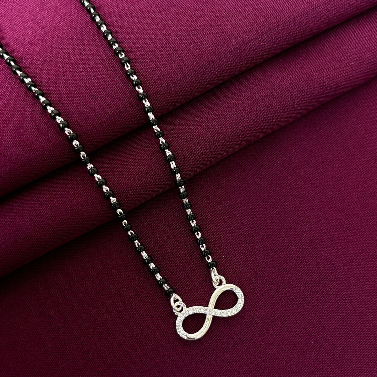 Silver infinity necklace on a purple fabric background