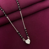 Mangalsutra with a heart-shaped pendant on a maroon fabric background