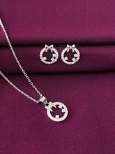 Silver necklace and earrings set on a purple fabric background