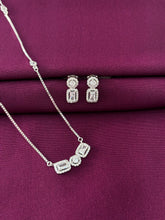 Silver jewelry set with necklace and earrings on a purple fabric background