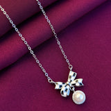 Silver necklace with a bow and pearl pendant on a purple fabric background