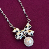 Necklace with a silver bow and pearl charm on a purple background