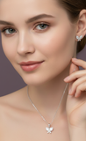 Woman wearing a butterfly necklace and earrings against a neutral background