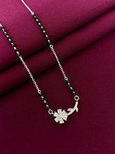 Silver mangalsutra with a floral pendant on a purple fabric background
