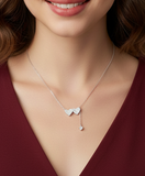 Necklace with a heart-shaped pendant worn by a model in a burgundy top.