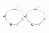 Two silver payal with blue evil eye charms on a white background
