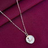 Silver necklace with a round pendant on a purple fabric background
