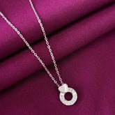 Silver necklace with a circular pendant on a purple fabric background