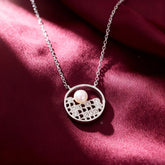 Silver necklace with a pendant featuring a pearl on a red fabric background