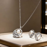 Silver jewelry set with pearl pendant on a wooden surface