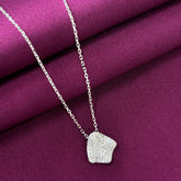 Silver necklace with a textured pendant on a purple fabric background