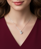 Silver necklace with a heart-shaped pendant worn by a person in a burgundy top.
