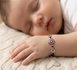 Child's hand wearing a silver bracelet with superhero design on a soft surface