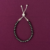 Beaded bracelet with black and silver beads on a purple background