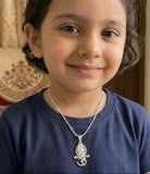 Child wearing a blue shirt and silver necklace with a pendant