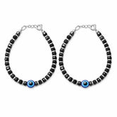 silver Pair of black beaded bracelets with blue evil eye charms on a white background