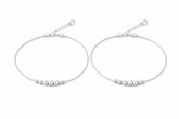 Pair of silver anklet with bead detailing on a white background