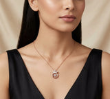 Woman wearing a rose gold necklace with a pendant against a beige background