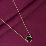 Necklace with a black pendant on a purple fabric background