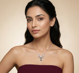 Woman wearing a silver necklace with a deer pendant against a beige background
