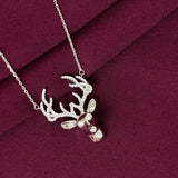 Silver deer head necklace on a burgundy fabric background