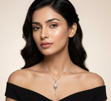Woman wearing a black off-shoulder top and a silver necklace with a pendant on a beige background