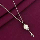 Silver necklace with a pearl pendant on a purple fabric background