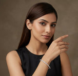 Woman wearing a black sleeveless top and bracelet on a brown background