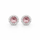 Pair of earrings with pink gemstones and diamond-studded halo on a white background