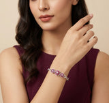 Woman wearing a bracelet with pink gemstones on a beige background