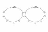 Two silver anklets with small round charms on a white background