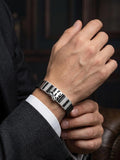 Hand wearing a silver bracelet with a dark background