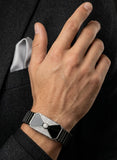 Hand wearing a silver watch with a black strap against a dark background