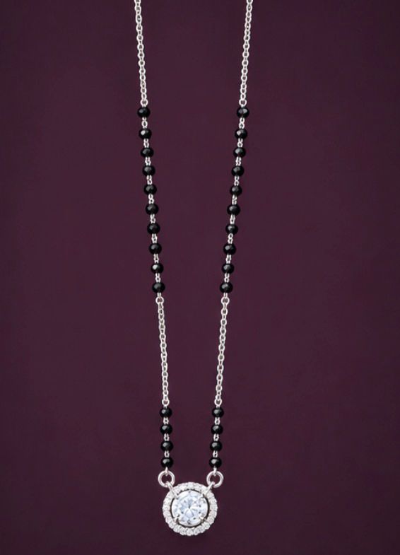 Necklace with black beads and a silver clasp on a purple background