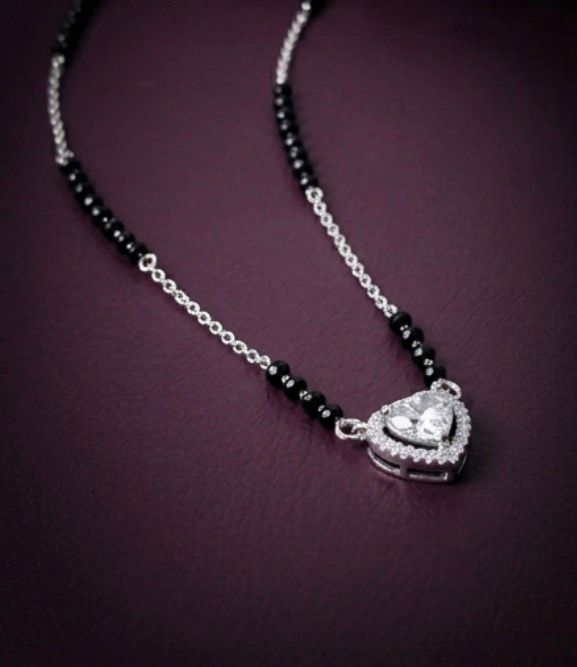 Necklace with black beads and a silver heart-shaped pendant on a dark background