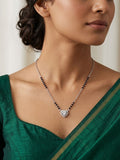 Woman wearing a green saree with a necklace featuring a heart-shaped pendant.