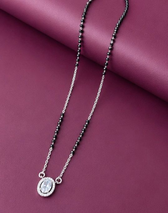Necklace with black beads and a silver pendant on a purple background