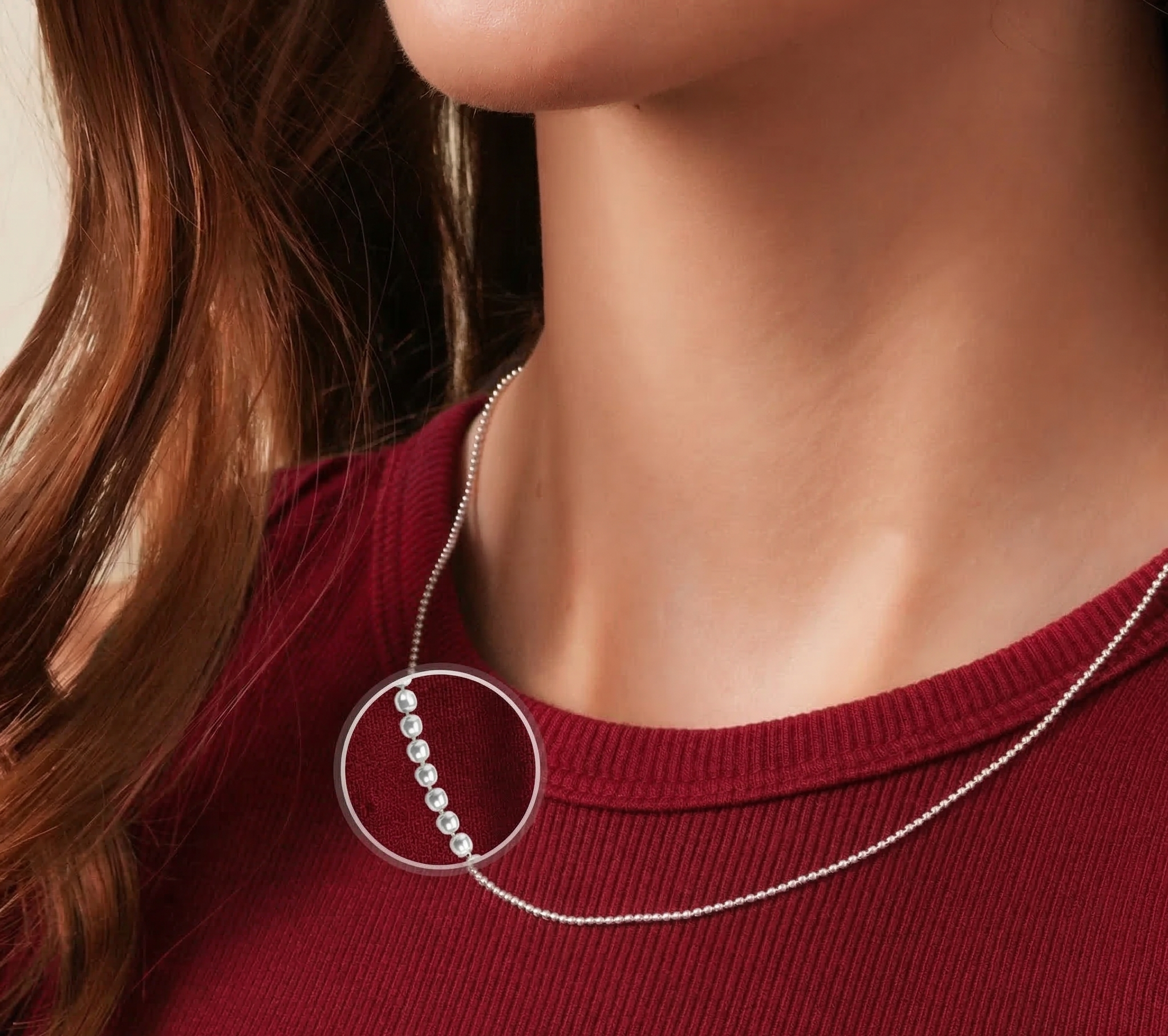 Close-up of a woman wearing a silver necklace with a circular pendant on a red top.