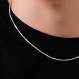 Silver chain necklace worn by a person on a black background