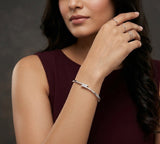 Woman wearing a silver bracelet and rings on a dark background