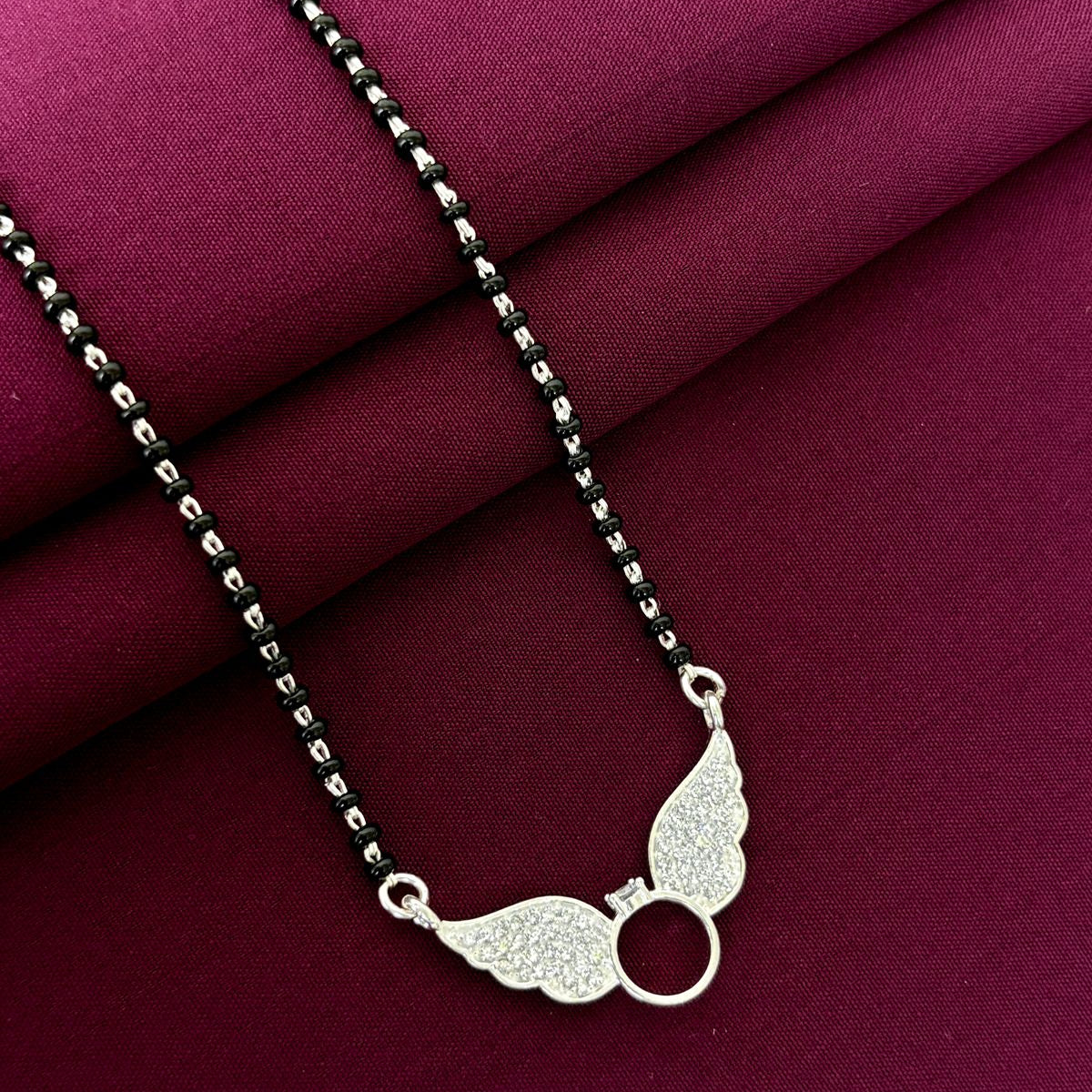 Silver necklace with a unique pendant on a maroon fabric background