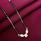 Silver necklace with black beads on a maroon fabric background