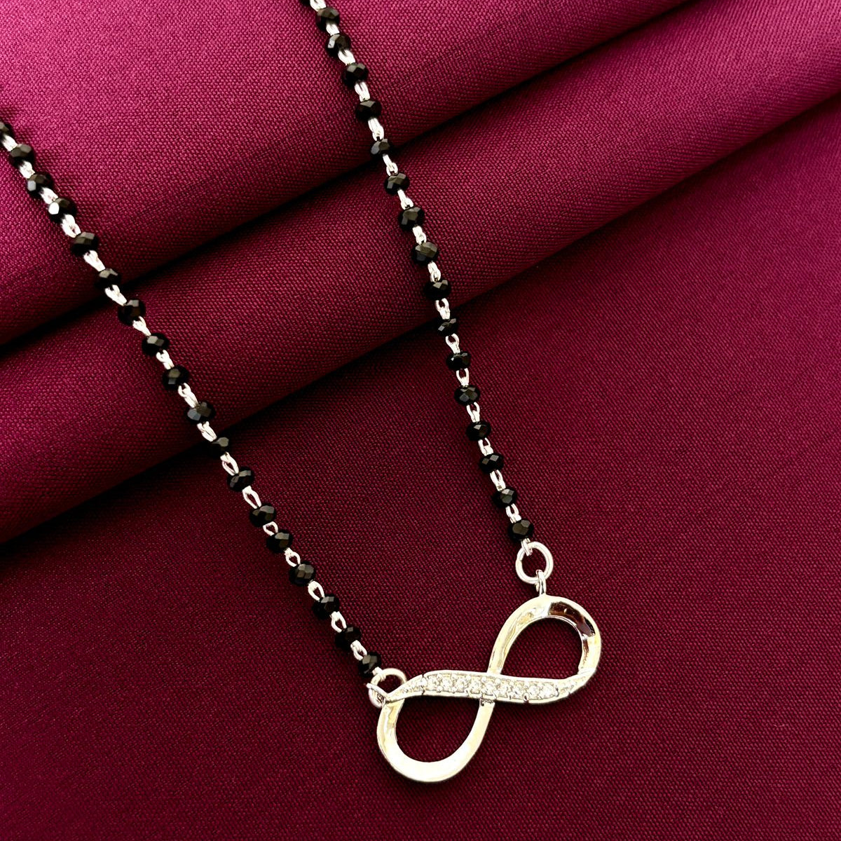 Necklace with an infinity symbol pendant on a red fabric background