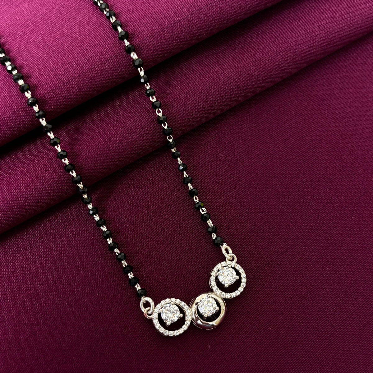 Necklace with three circular pendants on a purple fabric background