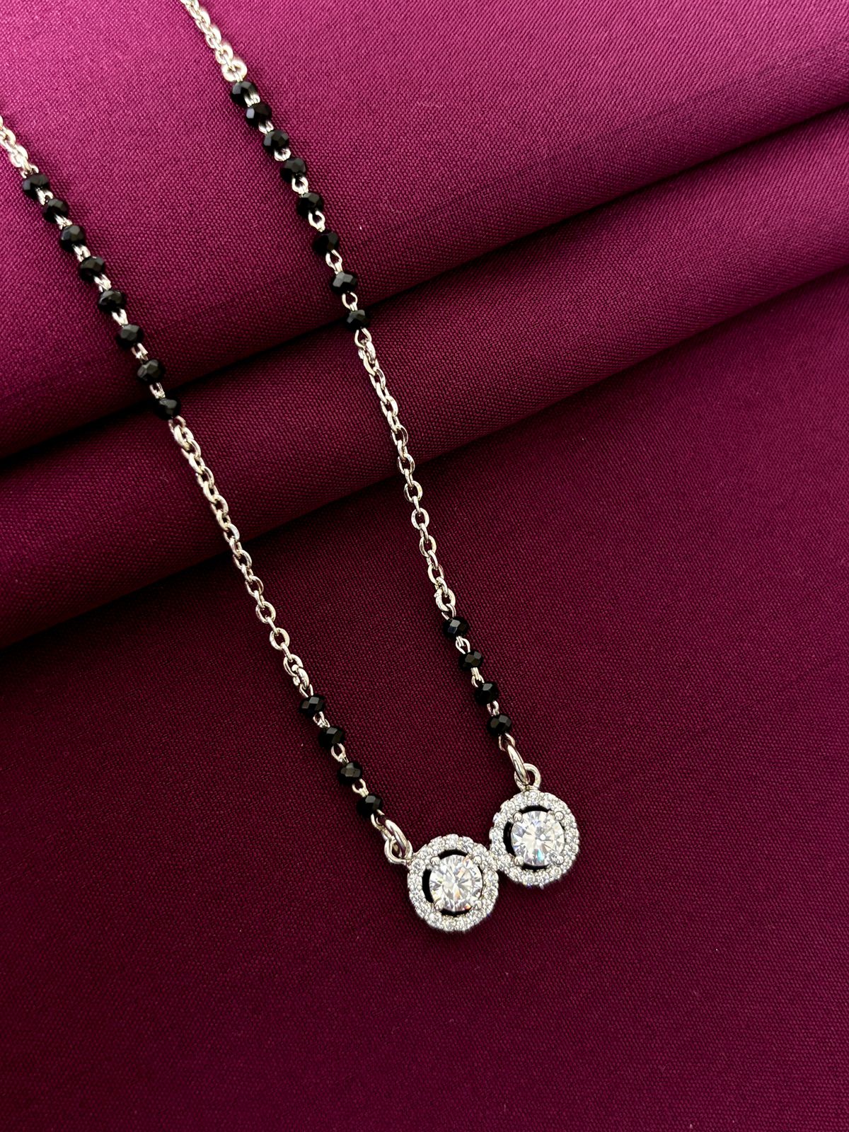 mangalsutra with a pendant on a maroon fabric background